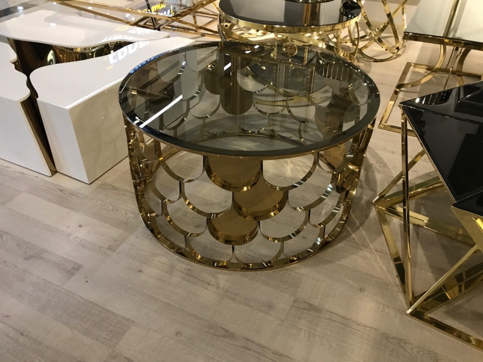 Tavolino rotondo con base in metallo dorato e piano in vetro fumé.