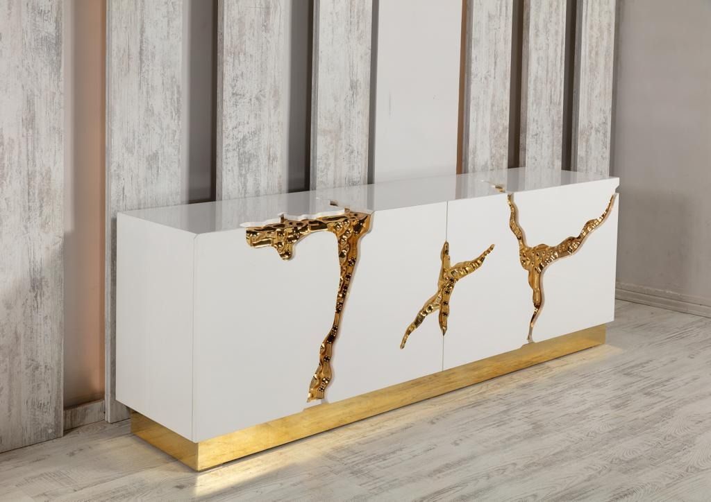 Credenza moderna bianca e oro con intricati dettagli dorati contro una parete strutturata.