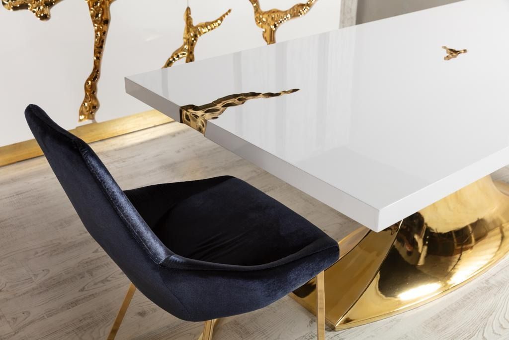 Tavolo bianco con dettagli dorati, sedia in velluto nero in una moderna e lussuosa sala da pranzo.