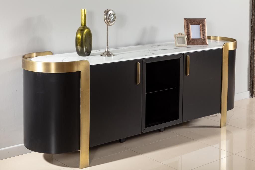 Mobiletto nero e oro con piano in marmo, che espone oggetti decorativi in ​​un ambiente neutro.