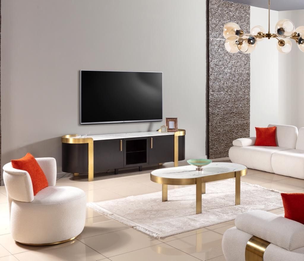 Soggiorno con TV, mobiletto porta TV nero e oro, divano bianco, poltrone e tavolino.