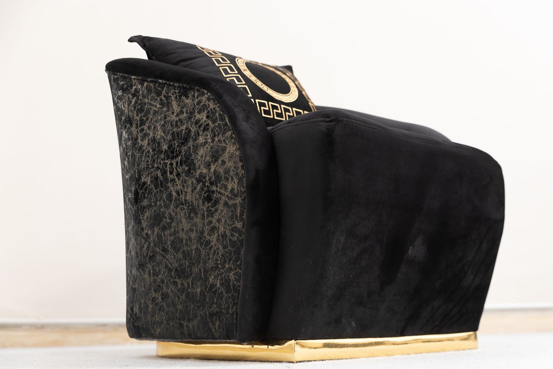 Poltrona in velluto nero con finiture dorate e schienale decorato, cuscino decorato.