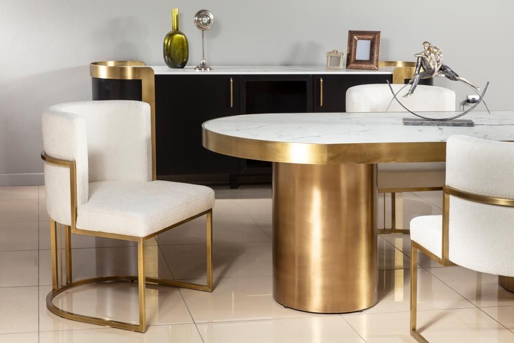 Poltrona sospesa bianca con cuscino giallo su una terrazza in legno. Una pianta in vaso è lì vicino, illuminata dalla luce del sole.