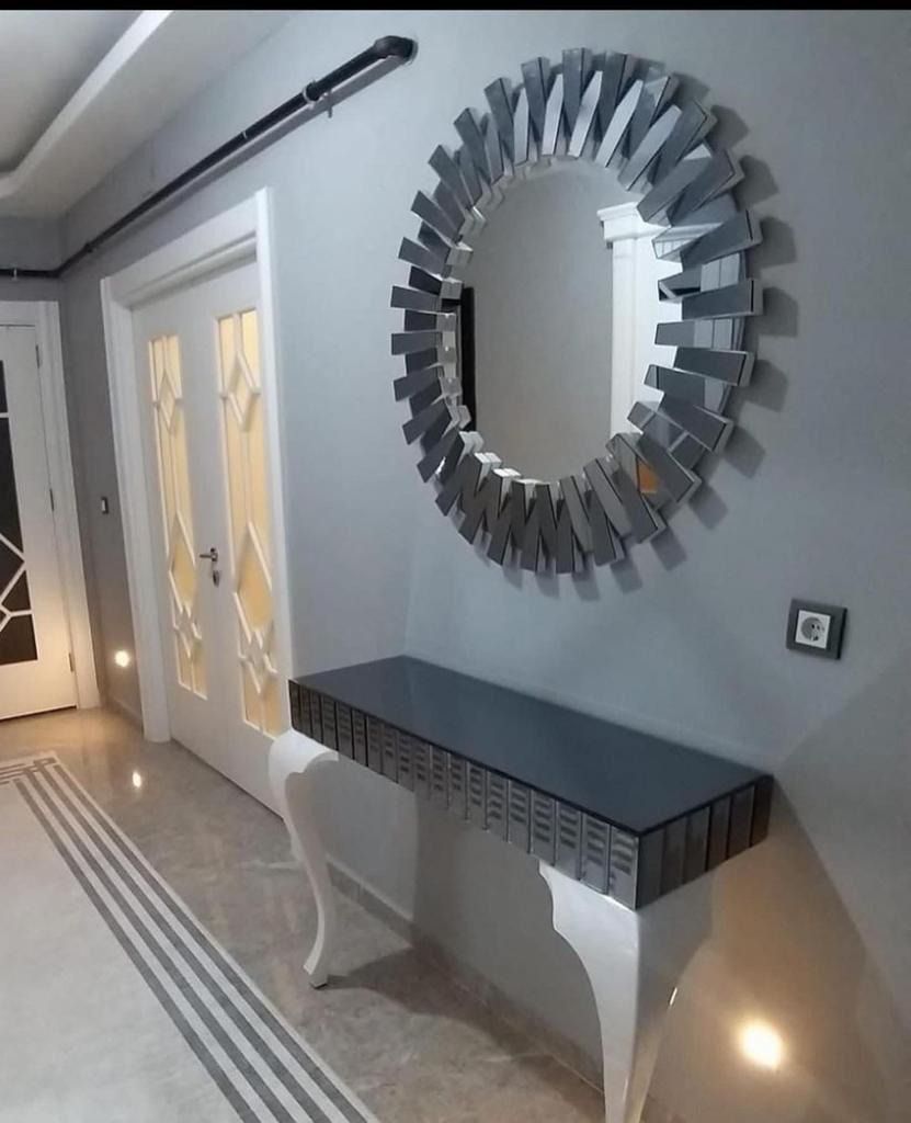 Specchio decorativo rotondo sopra una consolle con piano grigio in un corridoio. Porte bianche e pareti grigie.