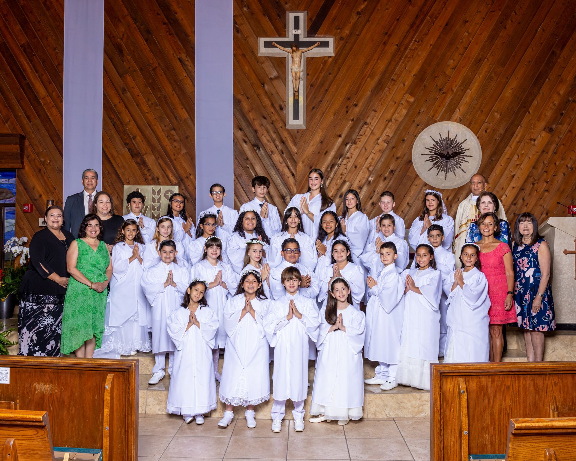 A group of children are posing for a picture in front of a wooden cross