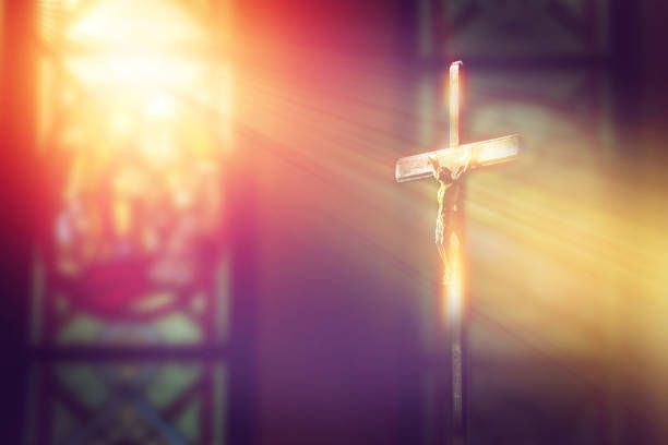 A cross in front of a stained glass window in a church.