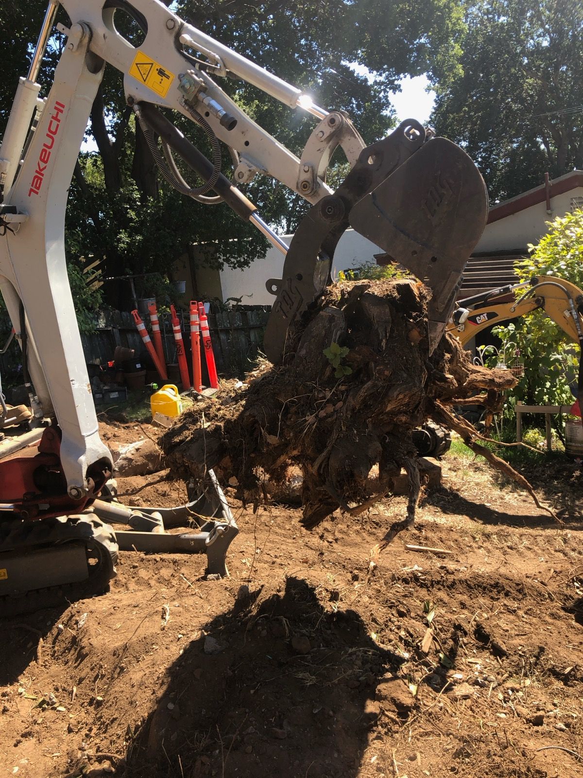 A large tree stump is being removed by an excavator.