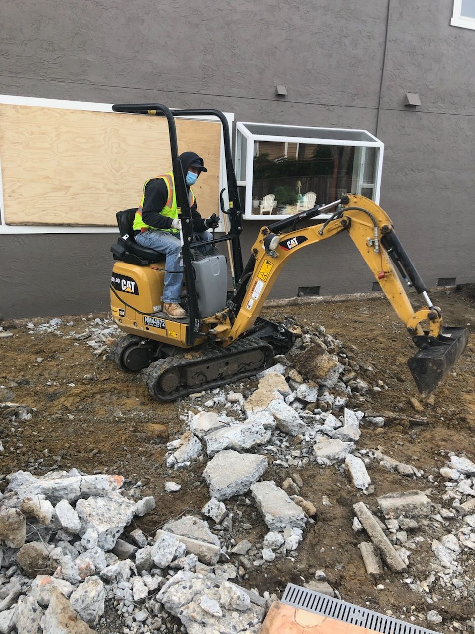 A man is driving a small excavator on a construction site.
