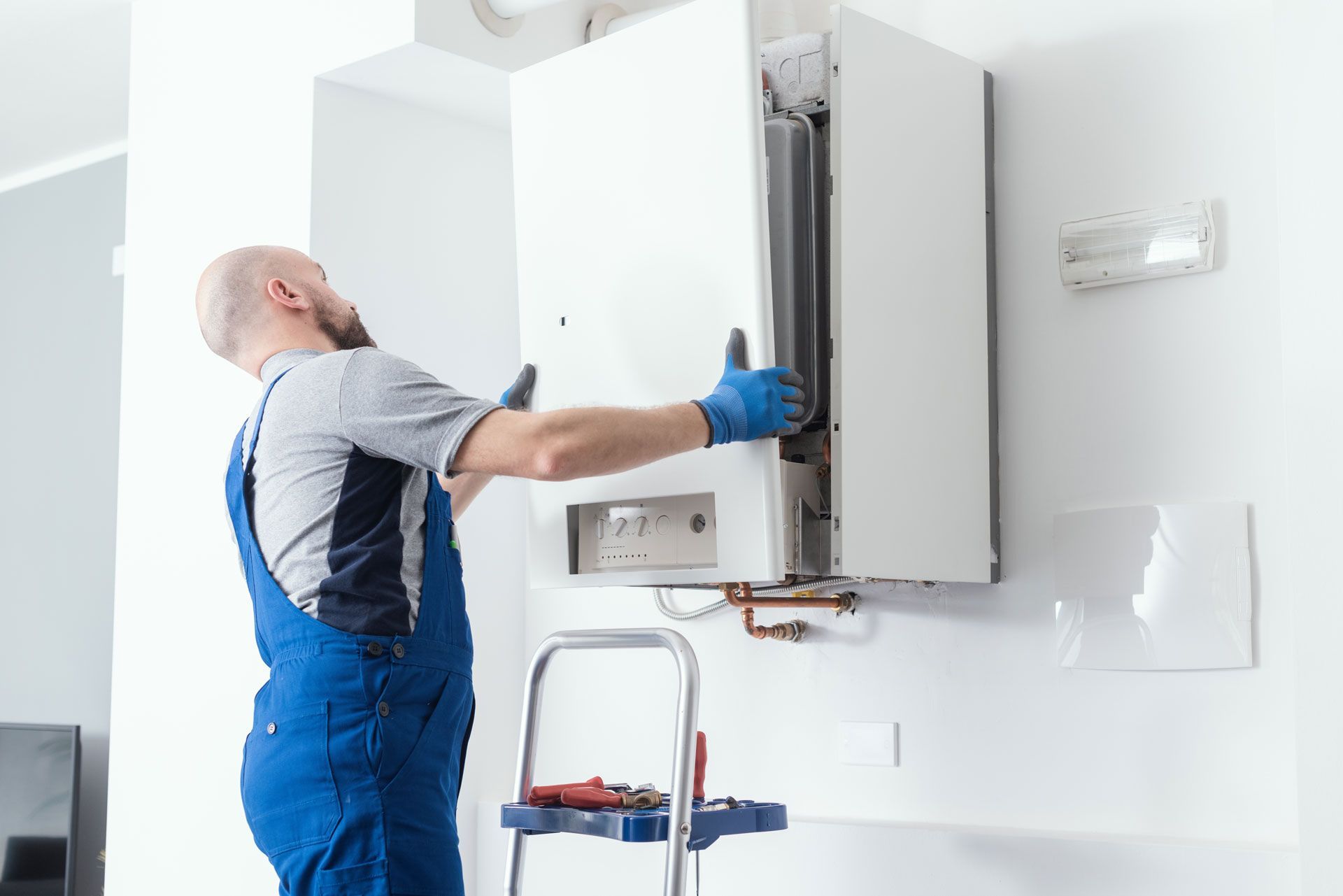 A man is installing a boiler on a wall.