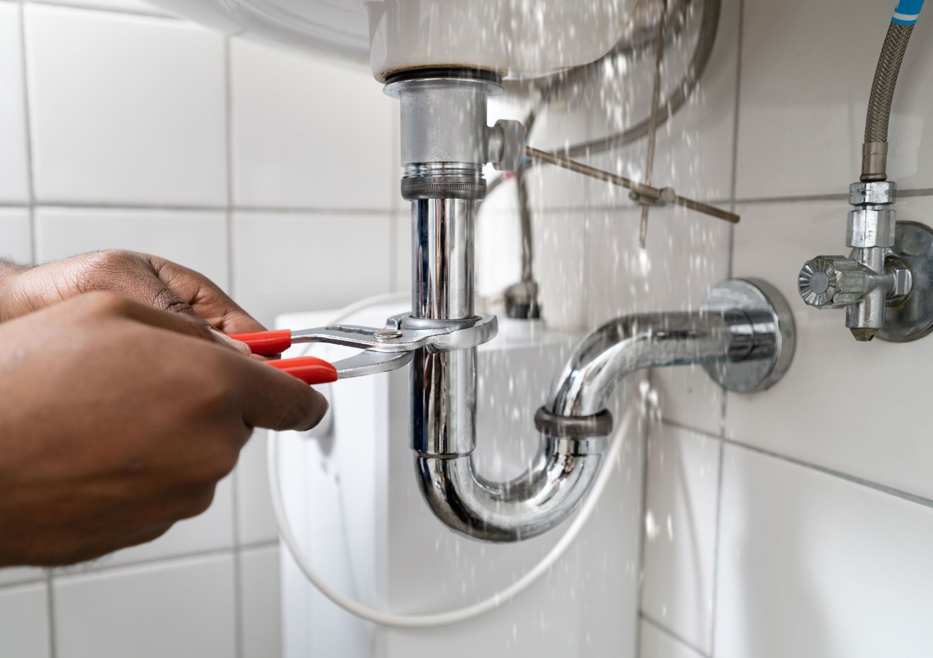 A person is fixing a sink pipe with a wrench.