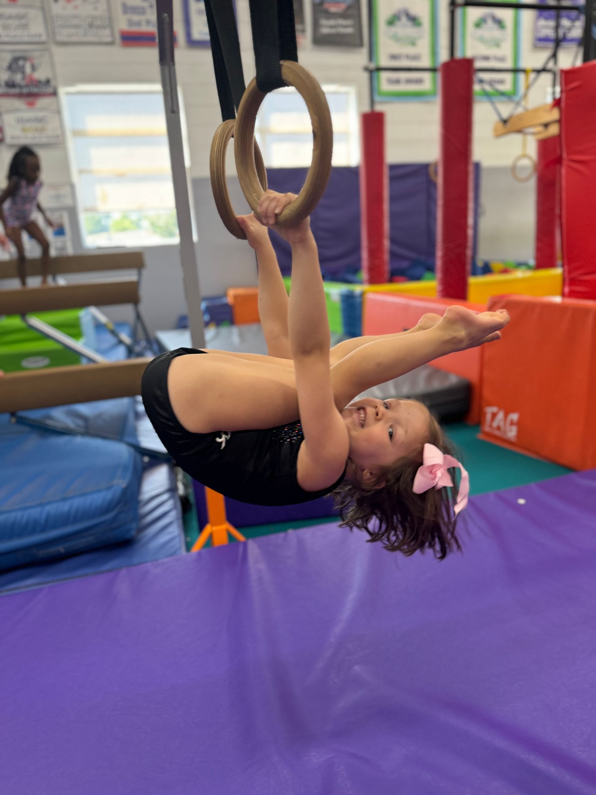 A little girl in a purple leotard is jumping in the air