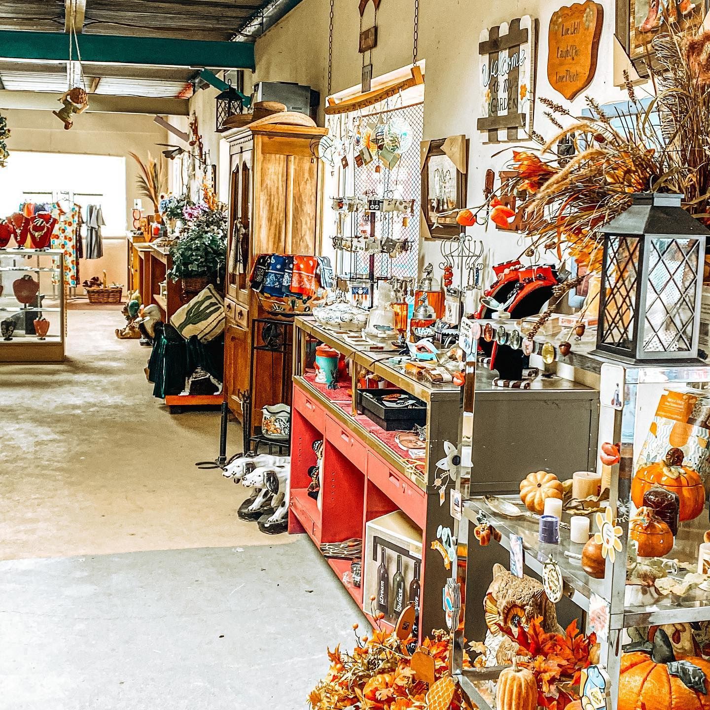 Rustic antique shop aisle with shelves of decor, glassware, and autumn-colored items