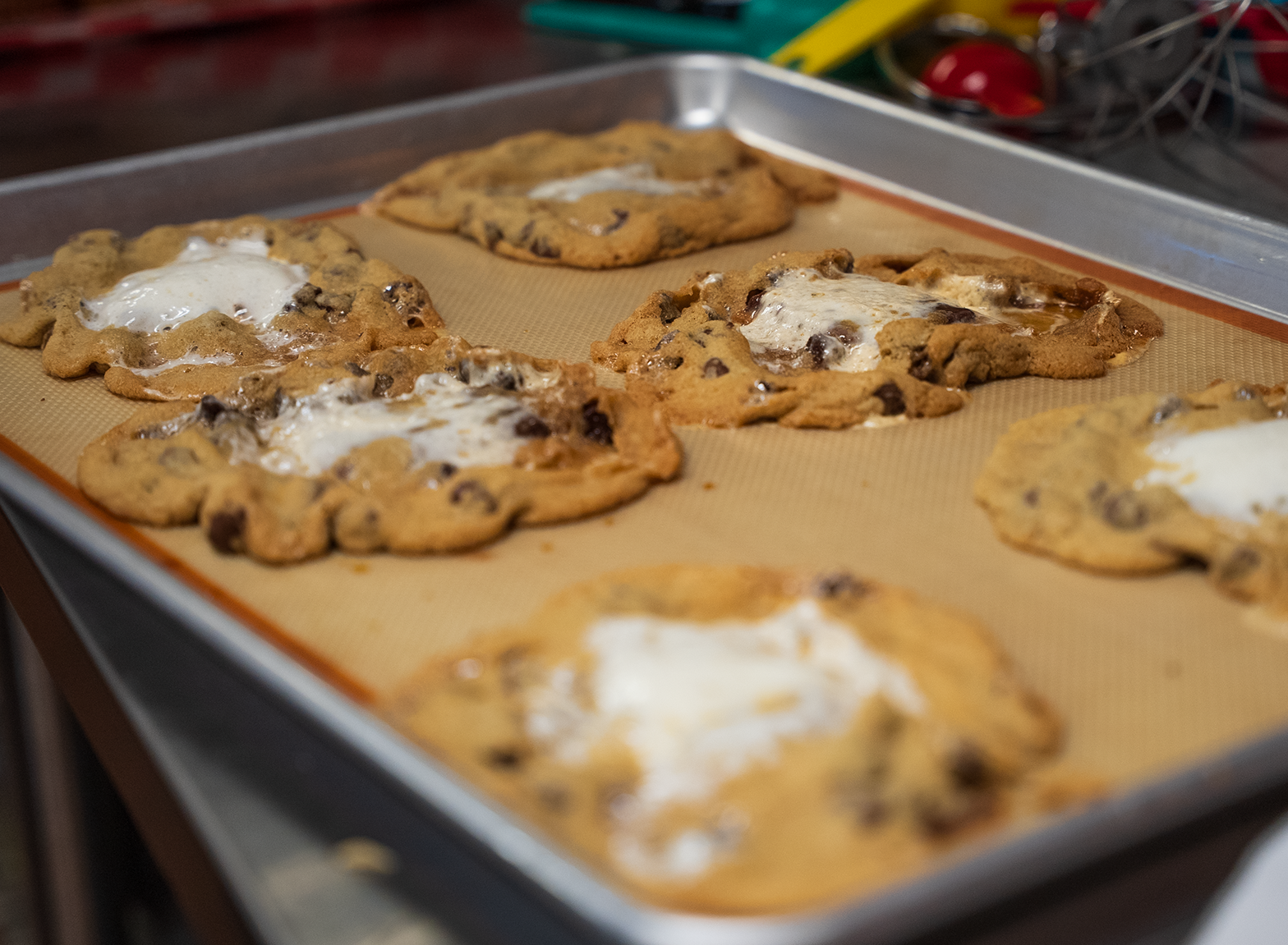 Cookies baking on a tray, dusted with powdered sugar, in a kitchen setting