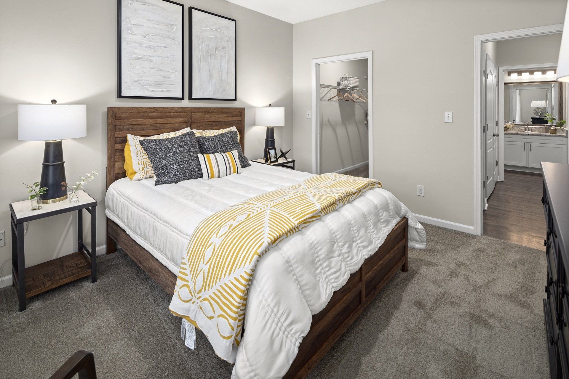 A bedroom with a bed , nightstand , lamps and a bathroom.