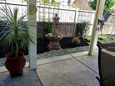 Stamped concrete patio with a patio cover and a water fountain for the water feature.