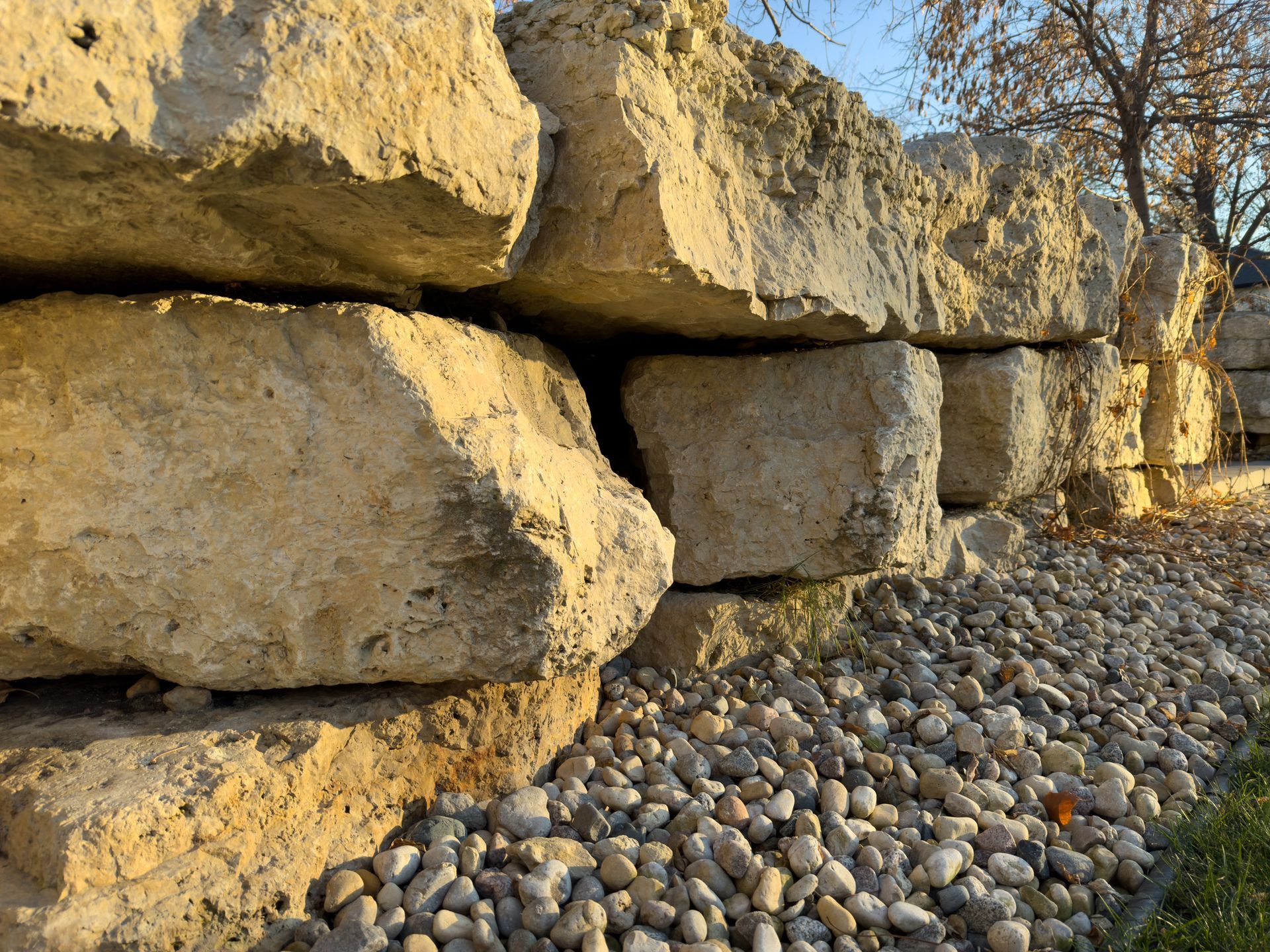 Stone retaining wall with small pebbles at base; outdoor setting.
