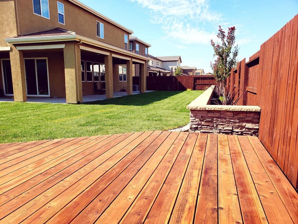 Landscaping with natural grass, a wood deck, retaining wall, concrete mow strip, sprinklers and drainage installed.