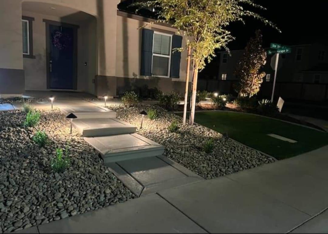 Front yard has concrete steps to the entry with landscape lighting and rock in the planter areas. There is a great landscape design of plants and a tree. There is also beautiful landscape lighting in the front yard.