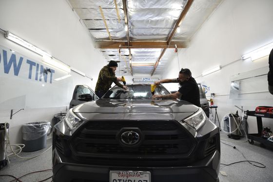 Two men are working on a toyota rav4 in a garage.