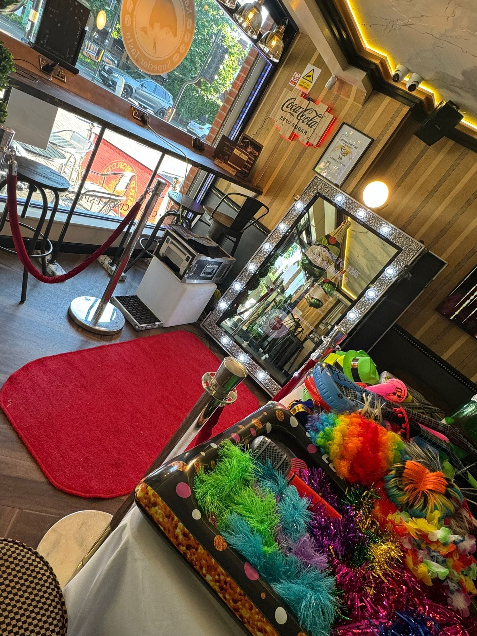 Photo booth setup with mirror, props, red carpet, and window view.