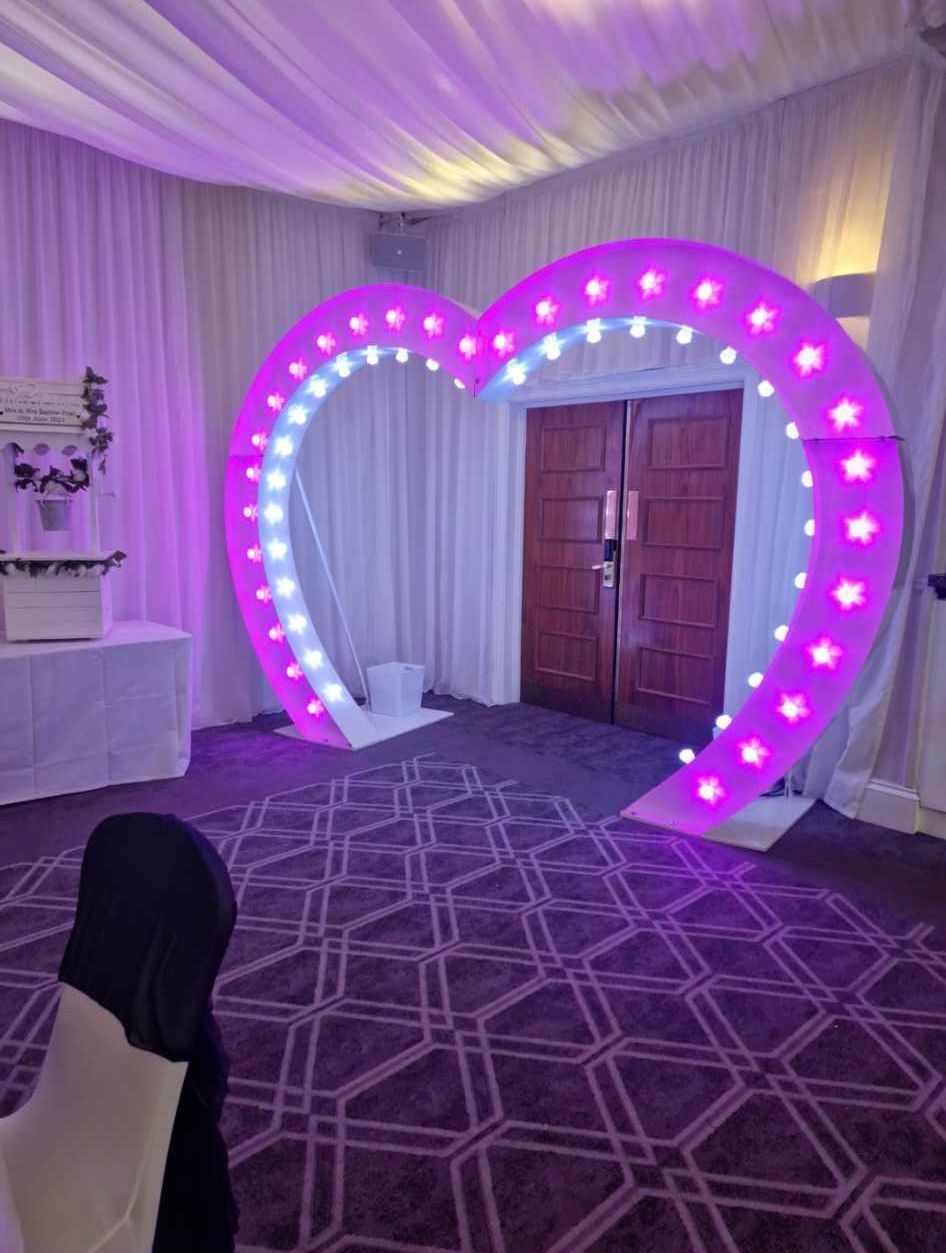 Purple heart-shaped archway with lights, set up in front of a doorway.