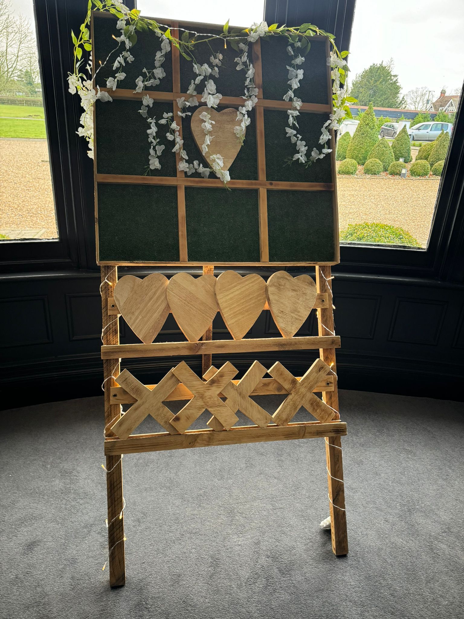 Wooden wedding sign with heart cutouts and floral decorations.