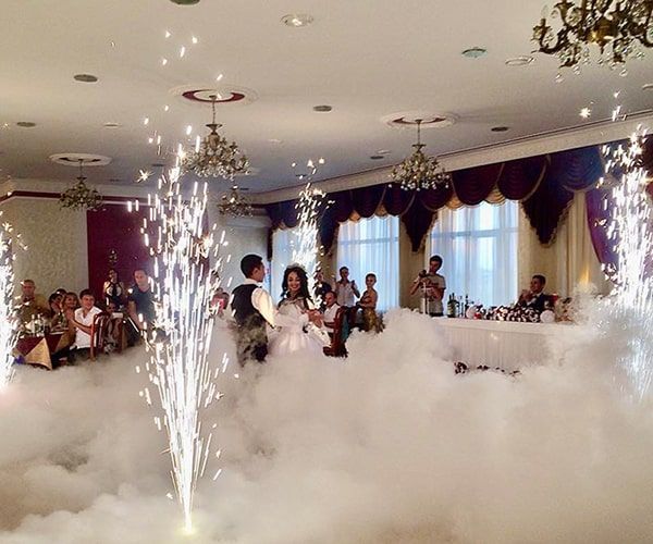 Couple dances surrounded by fog and fireworks in a decorated ballroom.