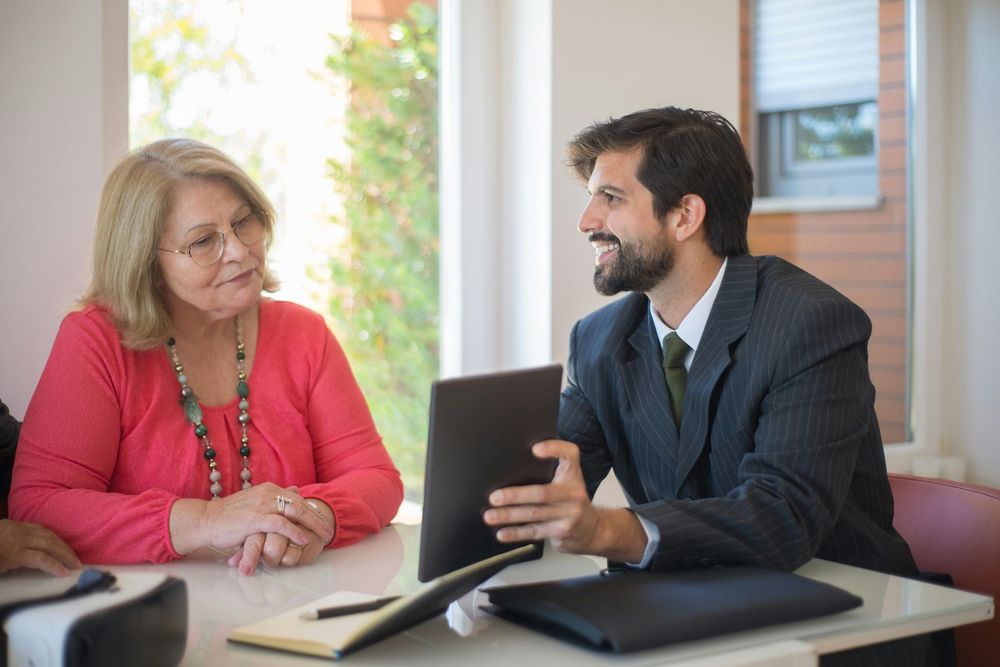 Two men in suits, one holding a tablet, gesturing outdoors.