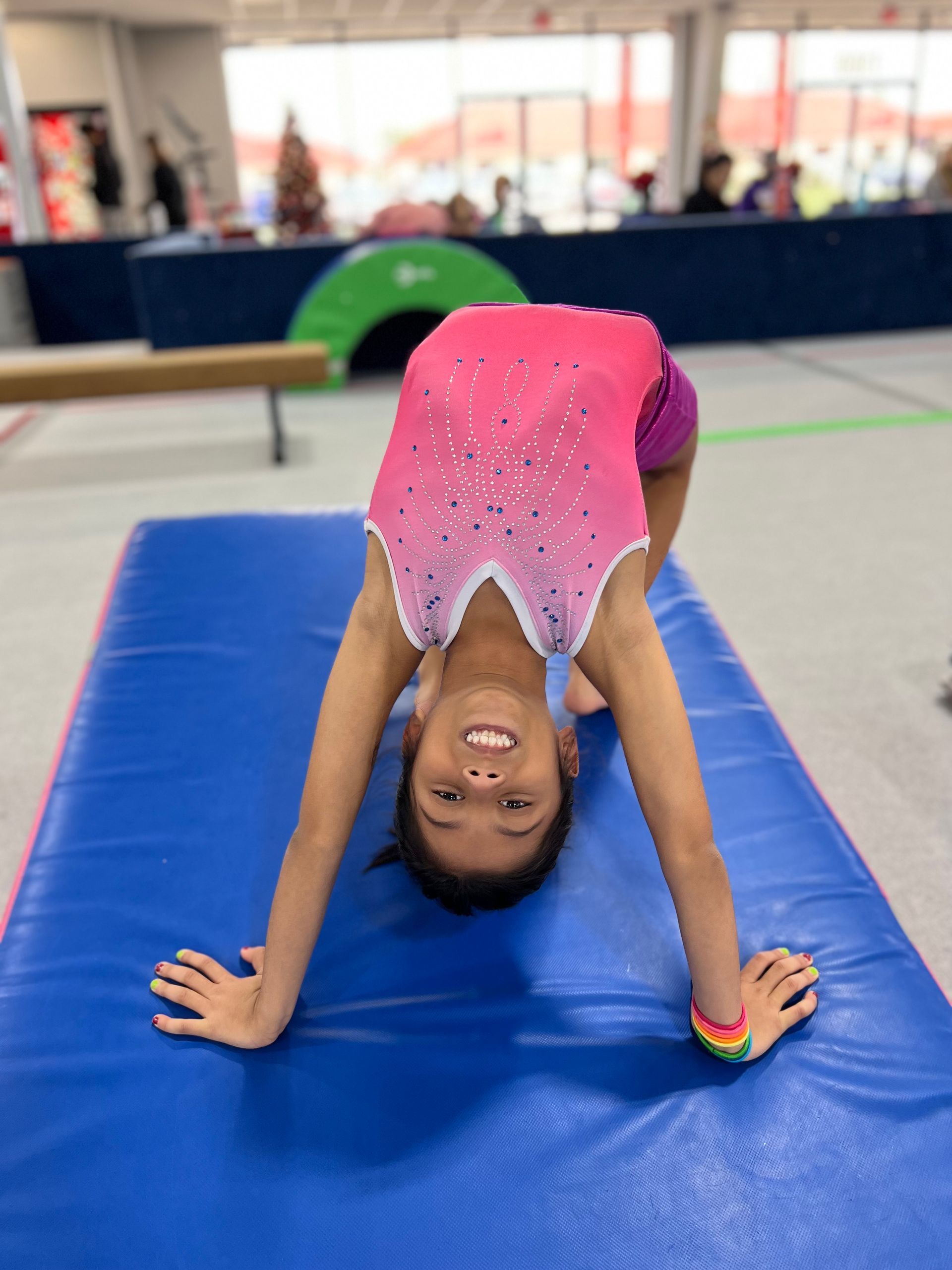 A young girl is doing a handstand on a blue mat.