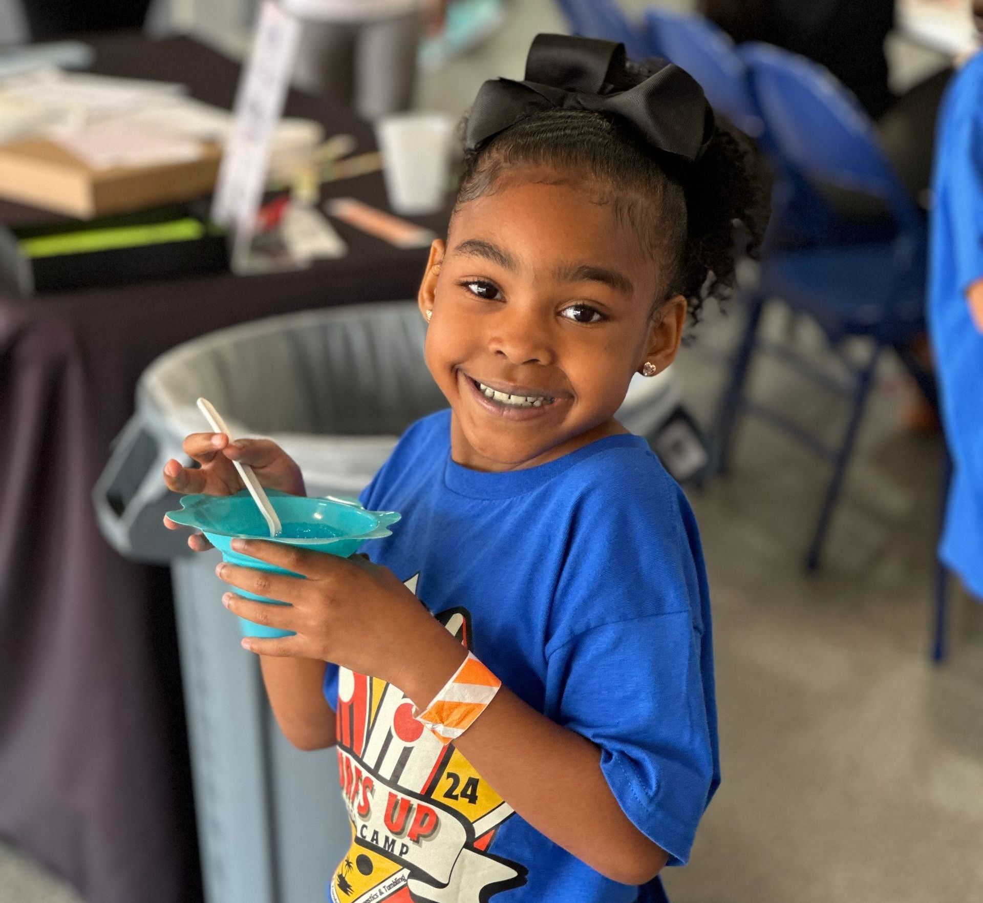 A little girl wearing a blue shirt with the number 24 on it