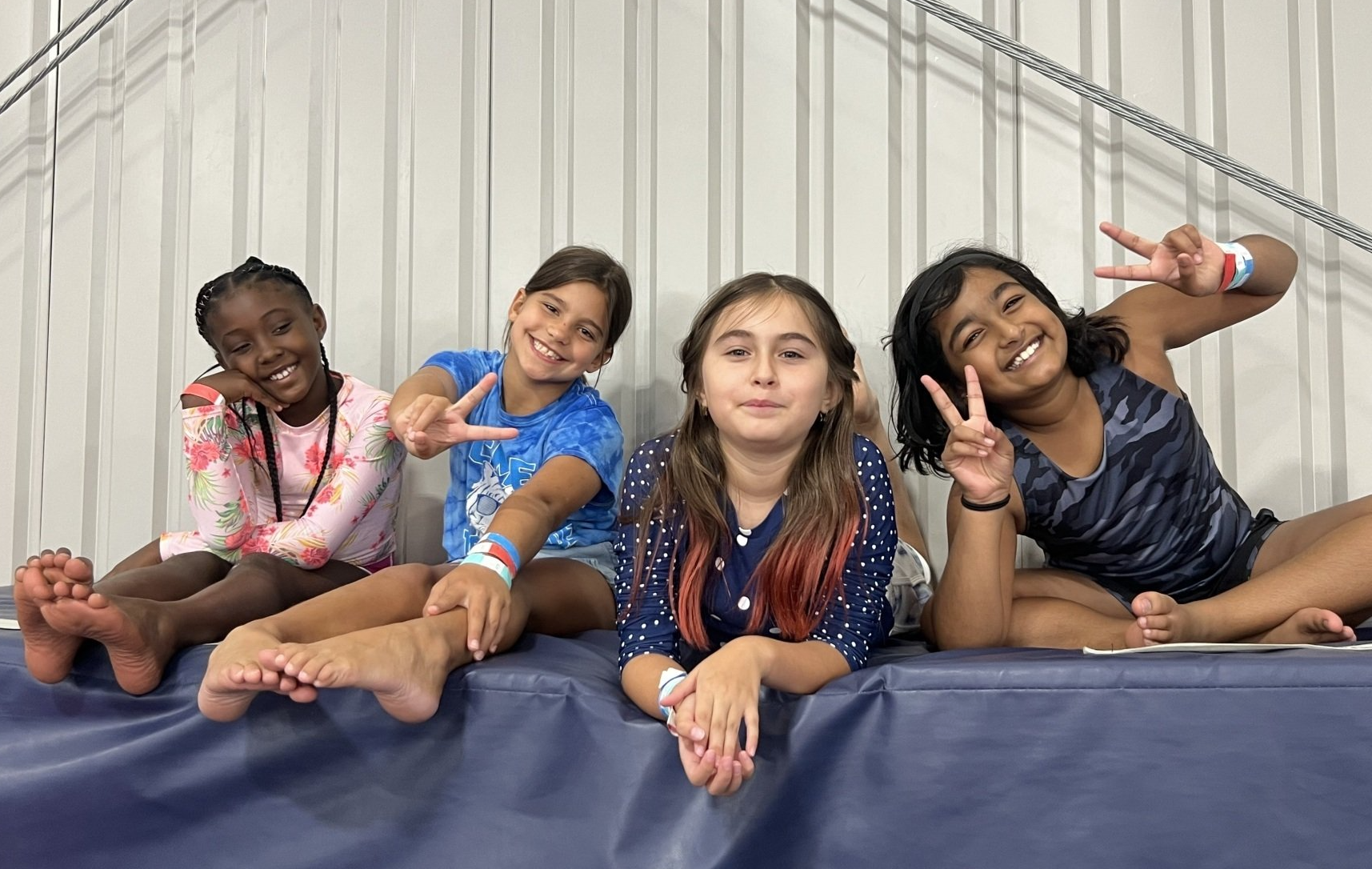 A group of young girls are posing for a picture while sitting on a mat.