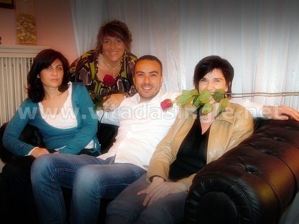 Un gruppo di persone sedute su un divano con una donna che tiene una rosa in bocca