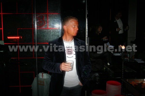 Un uomo è in piedi in una stanza buia con in mano un drink