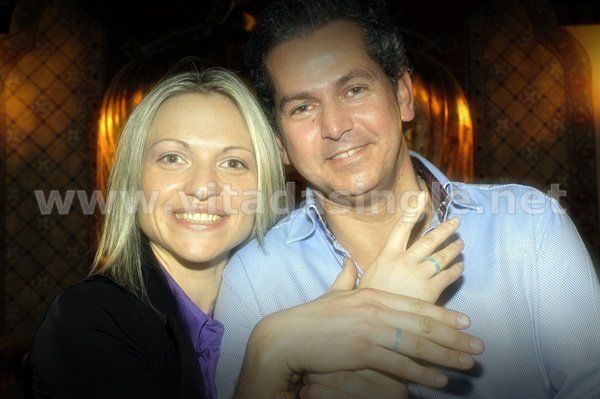 Un uomo e una donna posano con l'anello dei single per una foto con il sito Vitadasingle.net sullo sfondo
