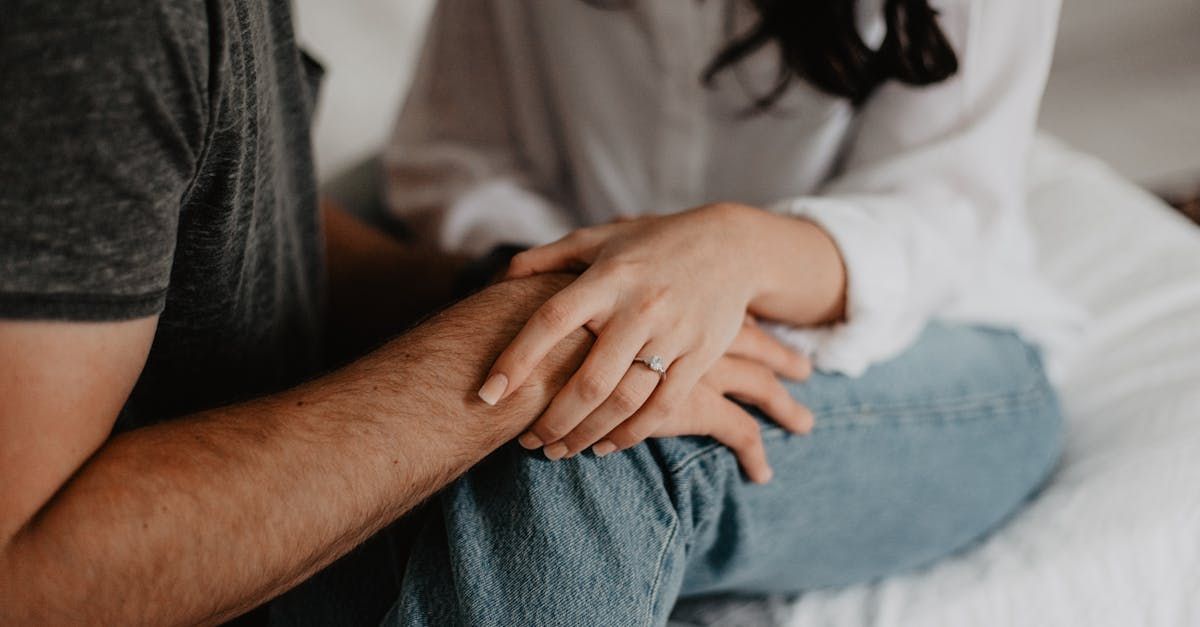 Un uomo e una donna sono seduti su un letto e si tengono per mano.