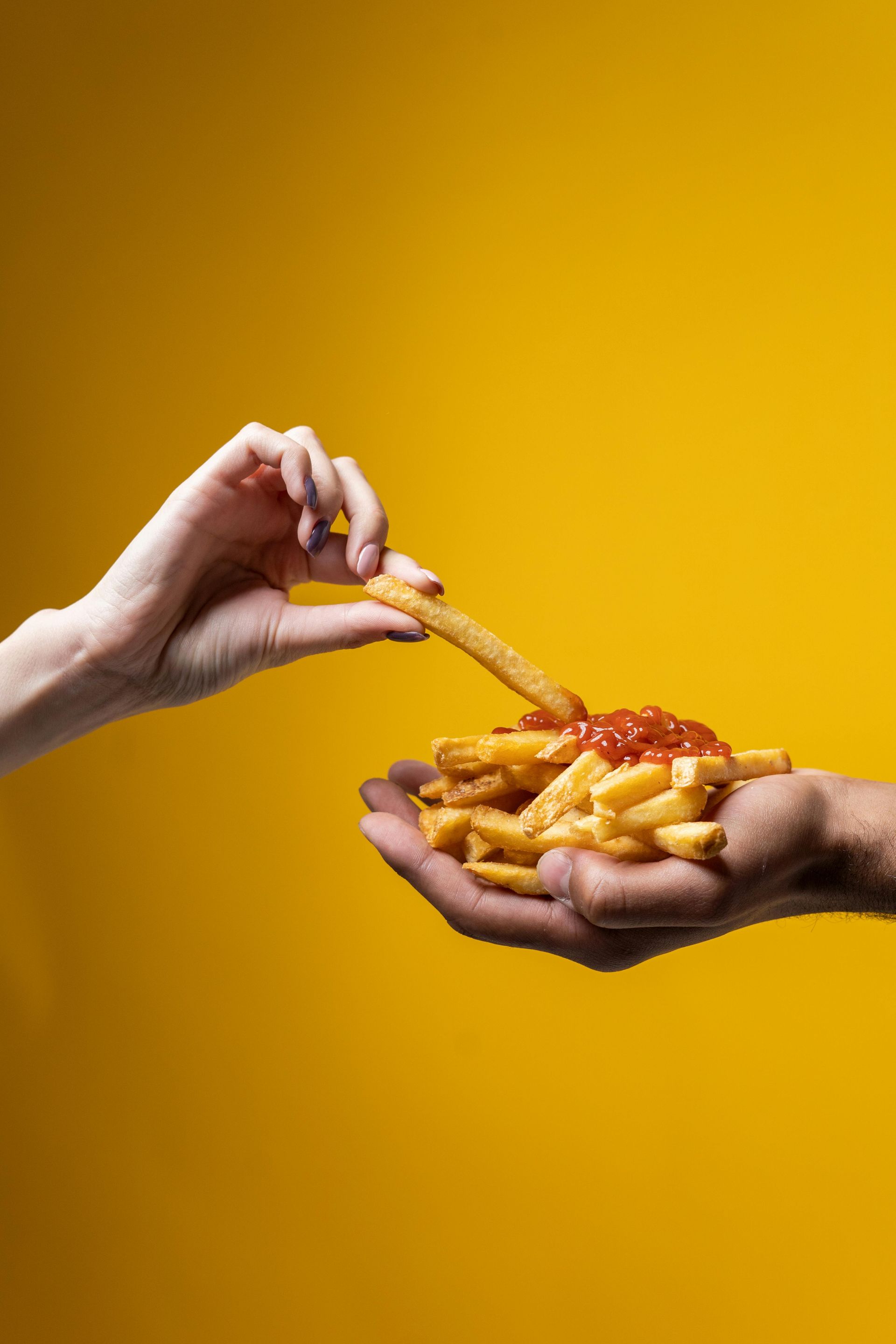 Una persona sta intingendo le patatine fritte nel ketchup.