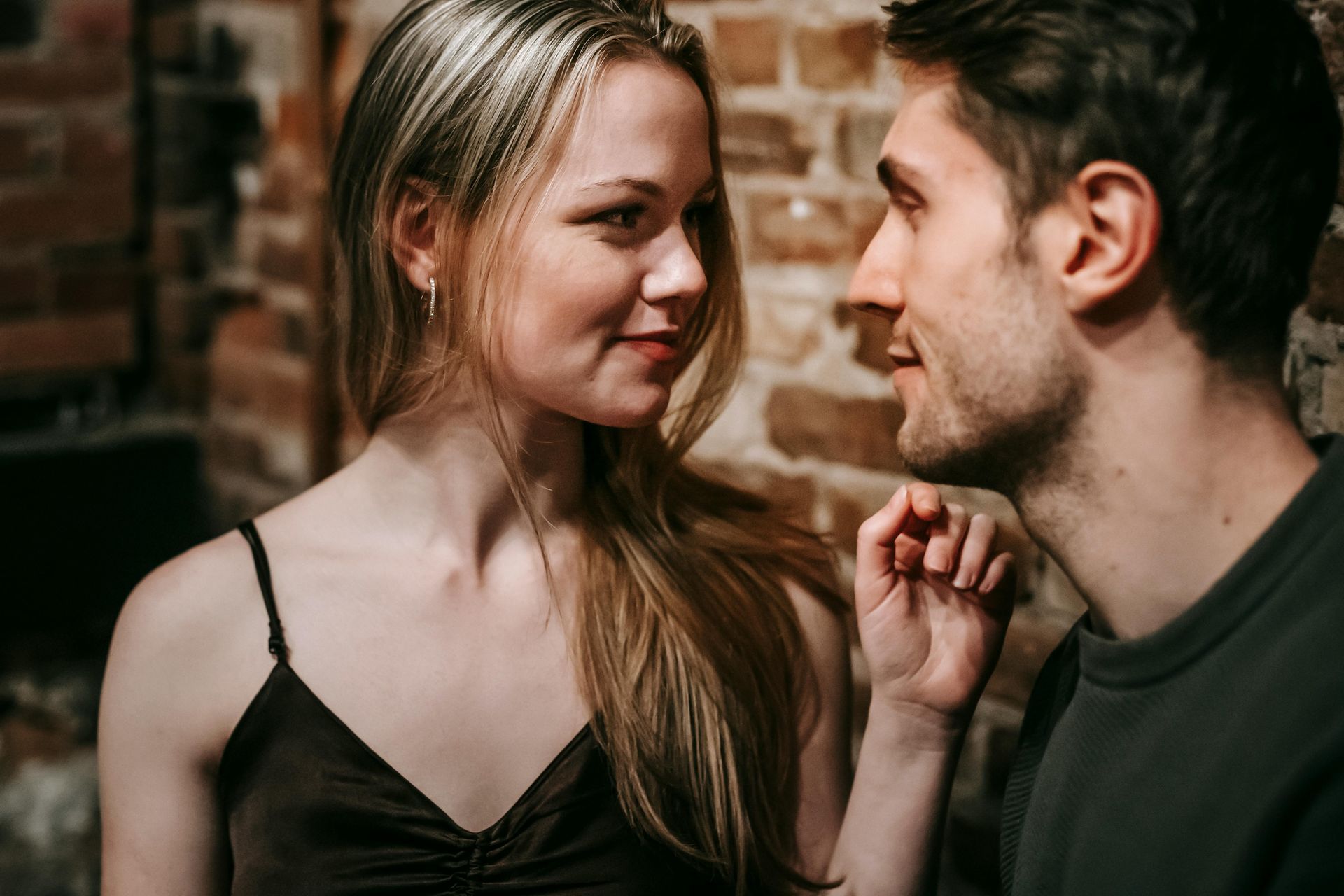Un uomo e una donna si guardano davanti a un muro di mattoni.