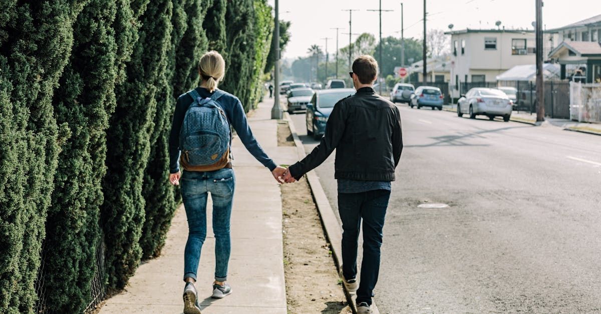 Un uomo e una donna camminano lungo un marciapiede tenendosi per mano.