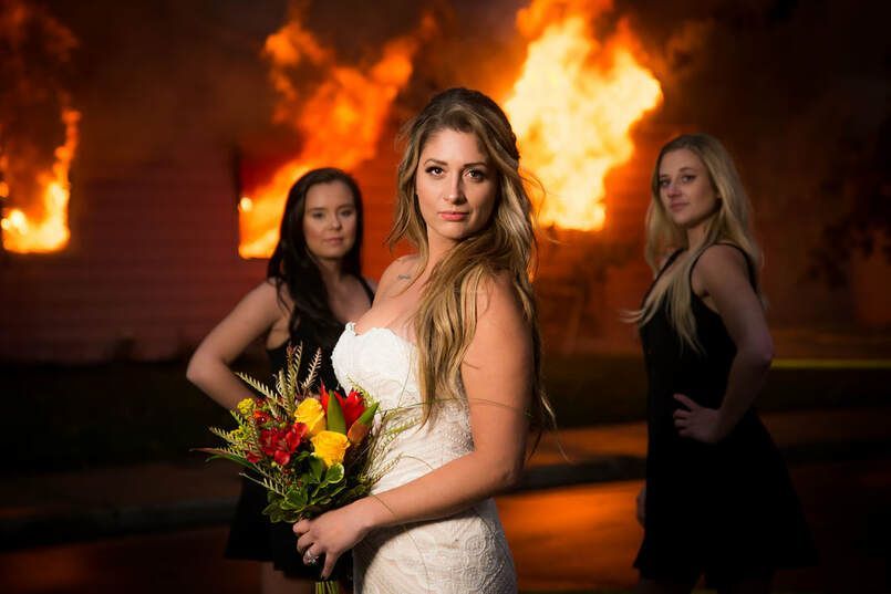 A woman in a wedding dress is holding a bouquet of flowers in front of a fire.