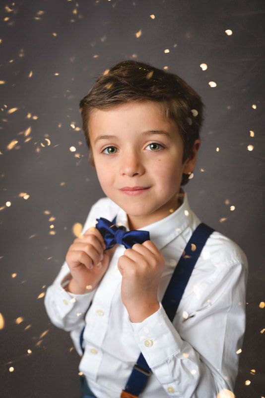 A young boy is wearing a bow tie and suspenders.