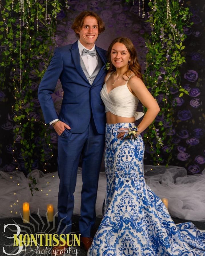 A man in a suit and a woman in a blue and white dress pose for a photo.