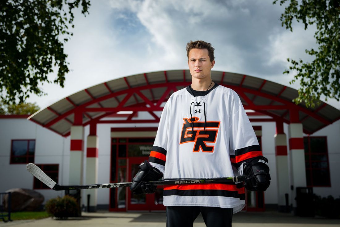 A man in a hockey jersey is standing in front of a building