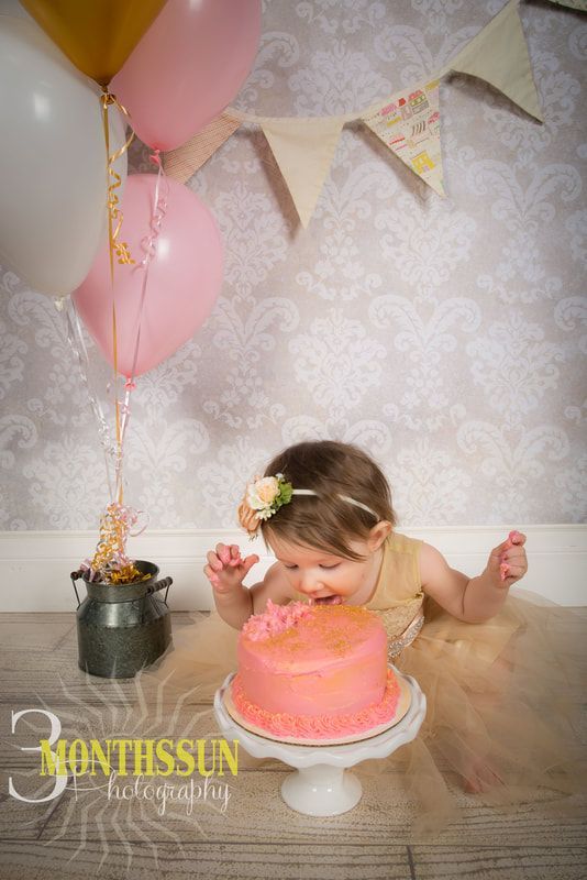 A little girl is eating a cake while holding balloons.