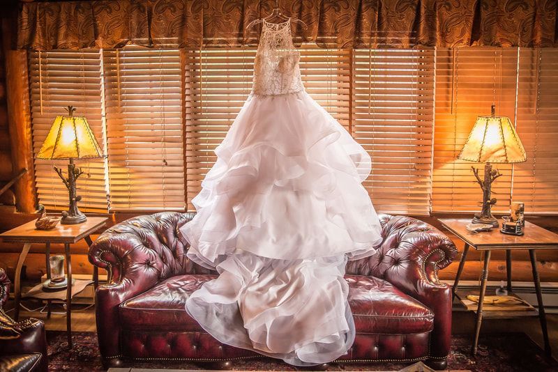 A wedding dress is hanging on a couch in a living room.