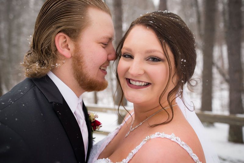 A bride and groom are posing for a picture in the snow.