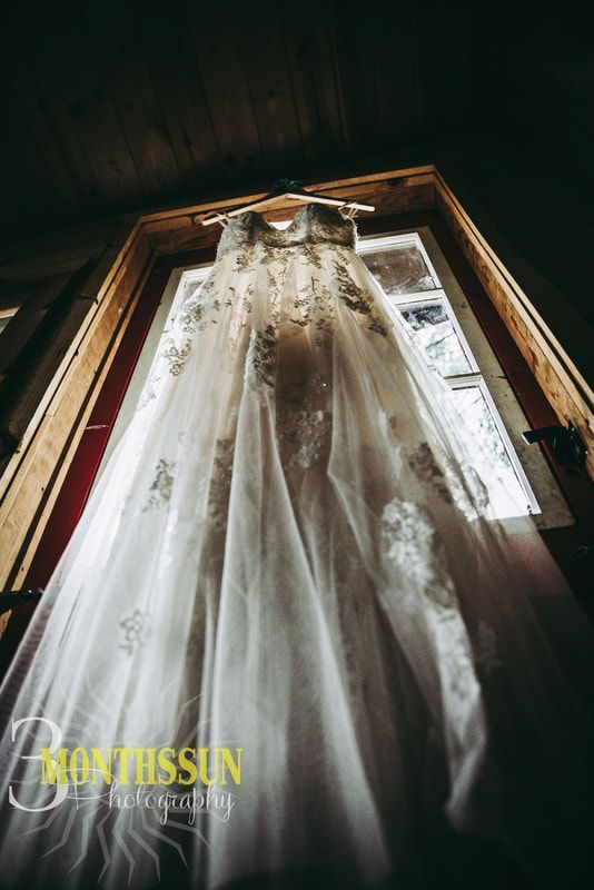 A bride 's wedding dress is hanging in a window.