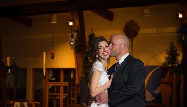 A man is kissing a woman on the cheek in a room.