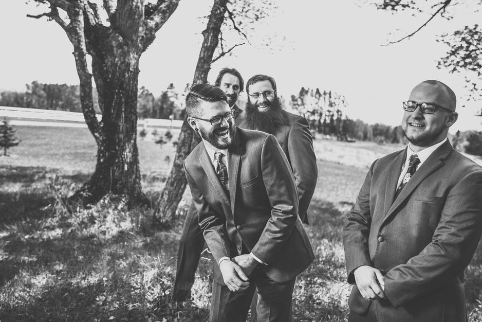 A group of men in suits and ties are laughing in a black and white photo.