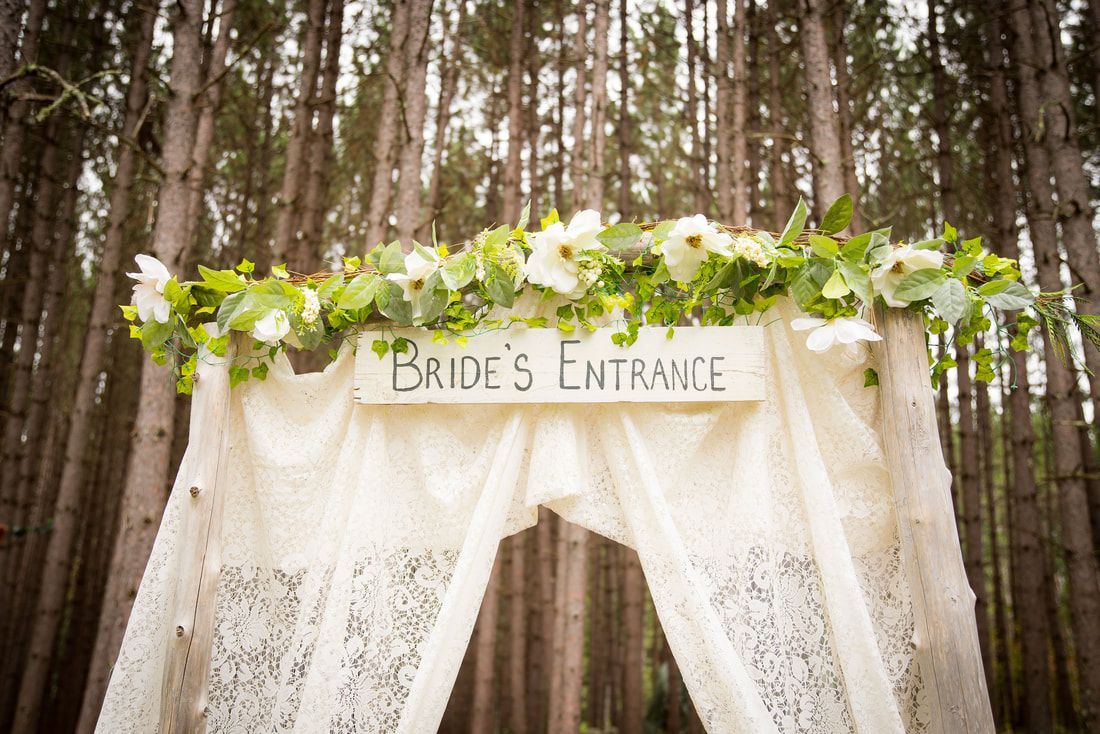 A bride 's entrance sign in the middle of a forest.