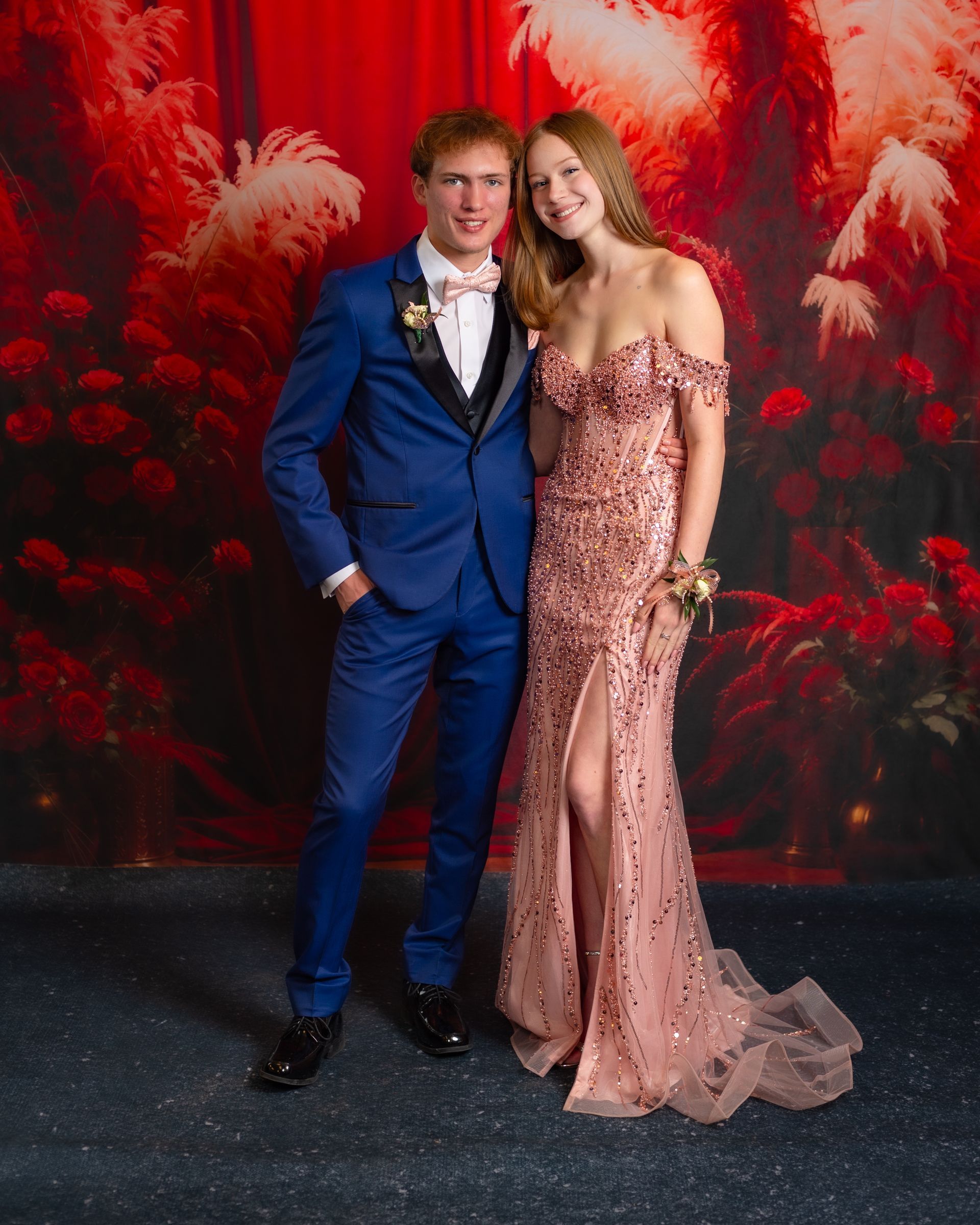 A man in a blue suit and a woman in a pink dress are posing for a picture.